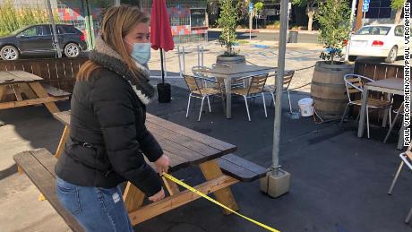 Angela Marsden of the Pineapple Hill Saloon and Grill in Sherman Oaks, California, measures the distance between tables at her outdoor dining area.