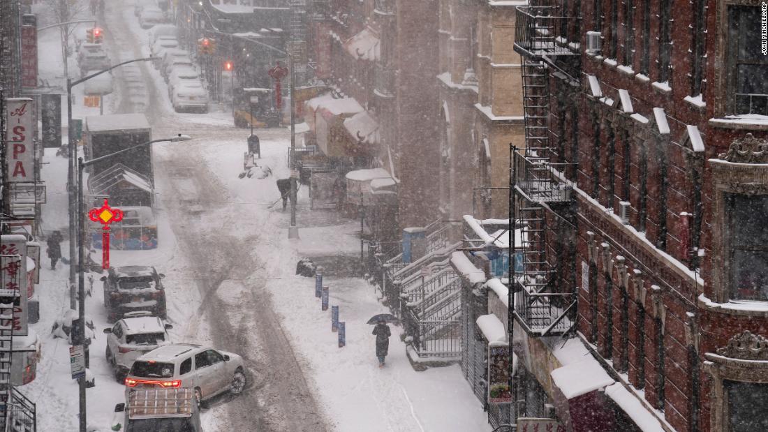 A pedestrian walks down a snow-covered sidewalk in the Chinatown neighborhood of New York on Monday.