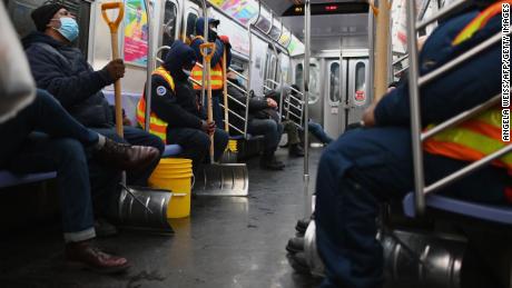 Workers hold snow shovels on the subway on Monday in New York City.