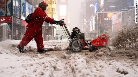 A worker clears snow off the sidewalks in Times Square on Monday.