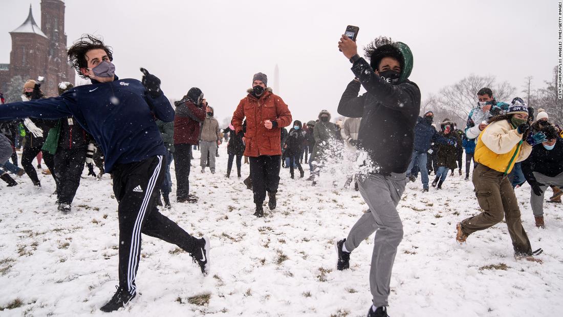 People take part in a snowball fight as snow blankets the National Mall in Washington, DC.