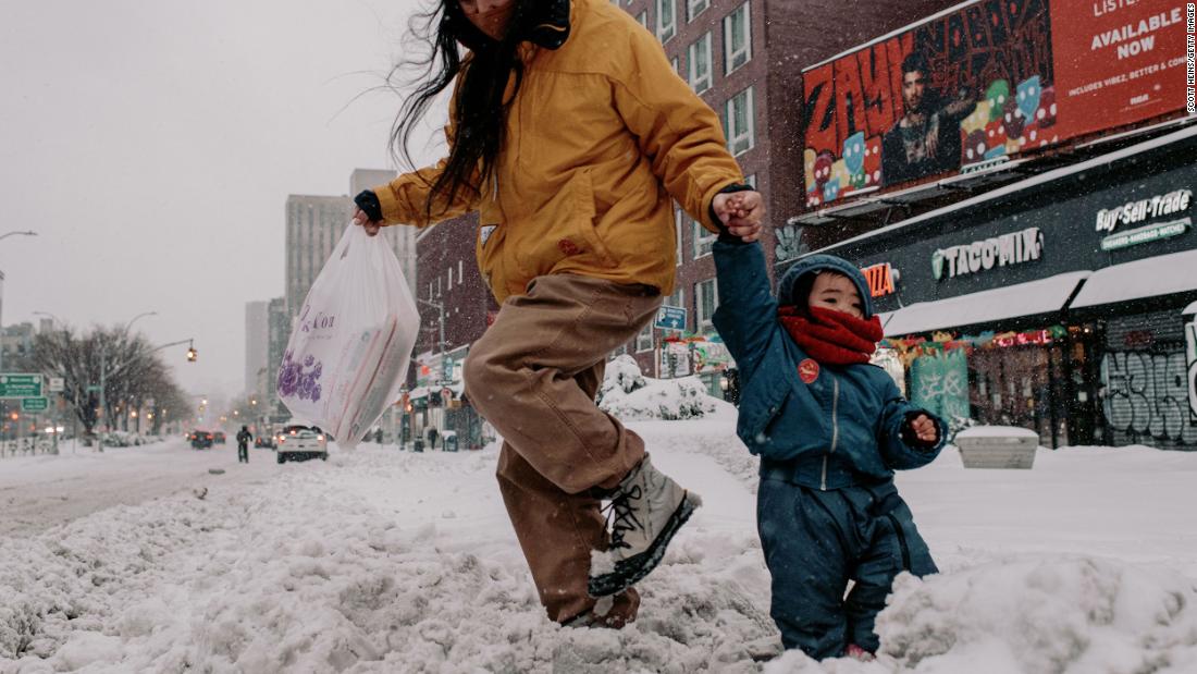 People walk through snow-covered streets in New York on Monday.