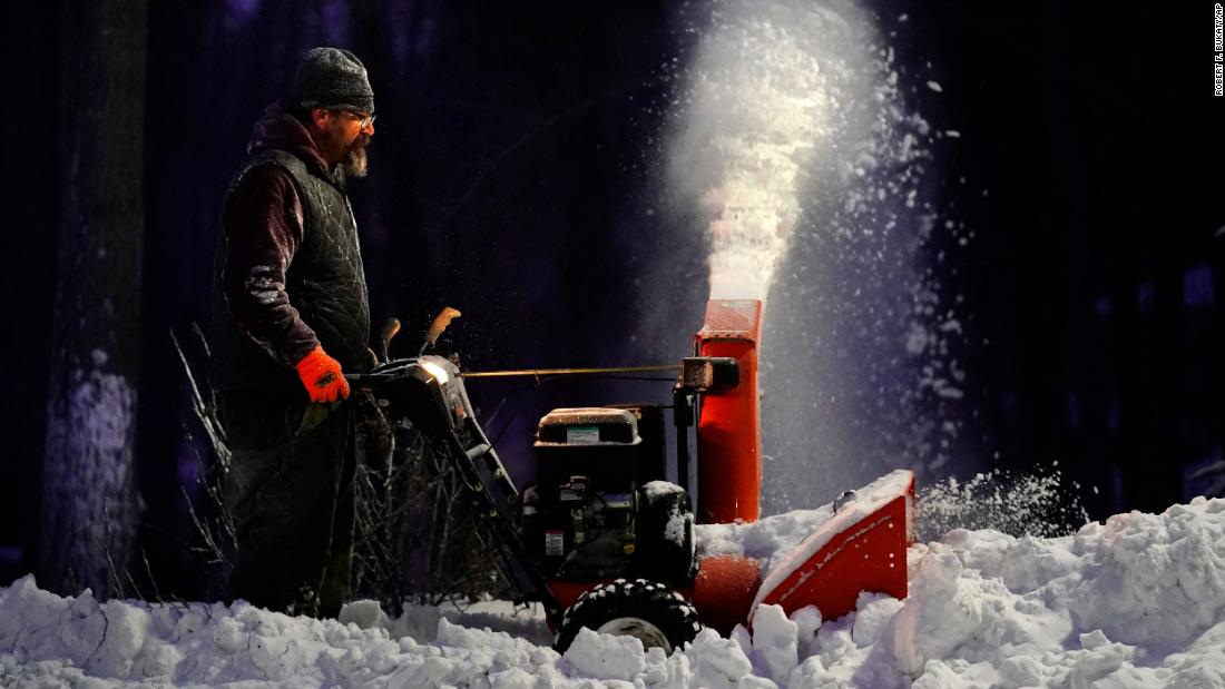 Rick Wallace clears a sidewalk with a snowblower in Freeport, Maine.