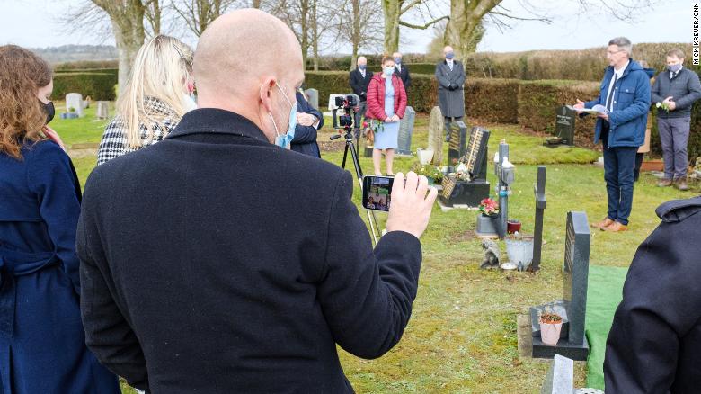 A family member streams the funeral service for Herbert John Tate live on Zoom, so others can watch from home. 