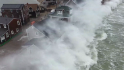 Massive waves crash over top of coastal homes