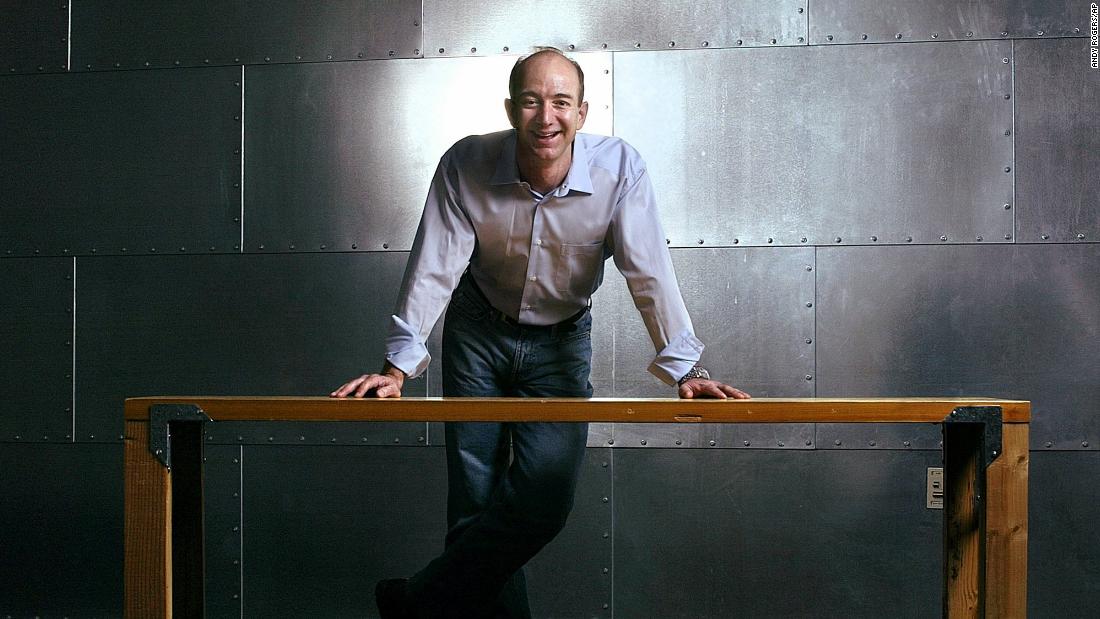Jeff Bezos stands with one of Amazon&#39;s trademark door-desks at the company&#39;s Seattle headquarters in 2004.