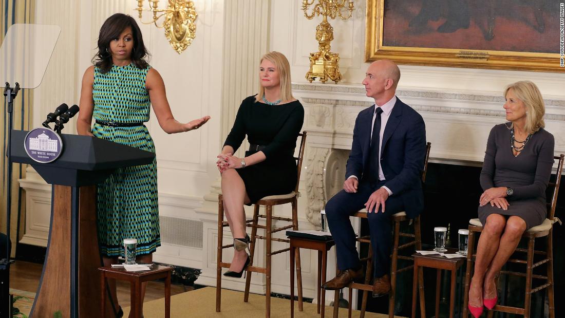 Bezos listens to first lady Michelle Obama at a White House event in 2016. The event announced commitments from more than 50 companies to hire and train veterans and military spouses. Bezos announced a commitment by Amazon to hire 25,000 more military veterans in the next five years.