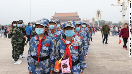 Čínští průkopníci v obličejových maskách se 1. října 2020 v čínském Pekingu účastní ceremonie zvedání vlajky na náměstí Nebeského klidu.