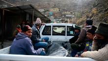 Relatives sit on the back a vehicle next to the body of a victim recovered from Raini village, outside a temporary morgue in Tapovan of Chamoli district on February 9, 2021.