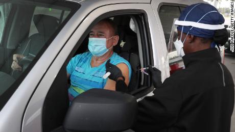 MIAMI, FLORIDA - JANUARY 13: Armando Bravo receives a COVID-19 vaccine from a healthcare worker at a drive-thru site at Tropical Park on January 13, 2021 in Miami, Florida. Miami-Dade County is distributing a limited number of coronavirus vaccines at the Tropical Park site, by appointment only, for seniors 65 years of age and older. (Photo by Joe Raedle/Getty Images)