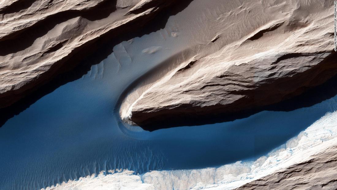 Although Mars isn&#39;t geologically active like Earth, surface features have been heavily shaped by wind. Wind-carved features such as these, called yardangs, are common on the Red Planet. On the sand, the wind forms ripples and small dunes. In Mars&#39; thin atmosphere, light is not scattered much, so the shadows cast by the yardangs are sharp and dark.