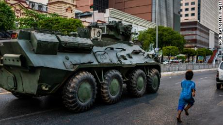 A child runs alongside a military armored vehicle moving along a street on February 14, 2021 in Yangon, Myanmar. 