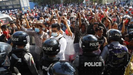 Residents and protesters face riot police as they question them about recent arrests made in Mandalay, Myanmar, February 13, 2021. 