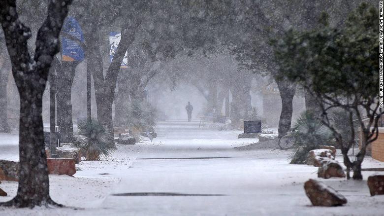 A pedestrian walks through the snow on the Angelo State University campus in Texas Sunday.