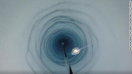 연구원들은 거대한 얼음 아래에서 무슨 일이 일어나고 있는지 모니터링하기 위해 우물을 파고 카메라를 낮추고 있습니다.