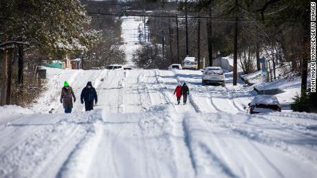 Pedestrians walk on an icy road on Monday, February 15, in East Austin, Texas. 