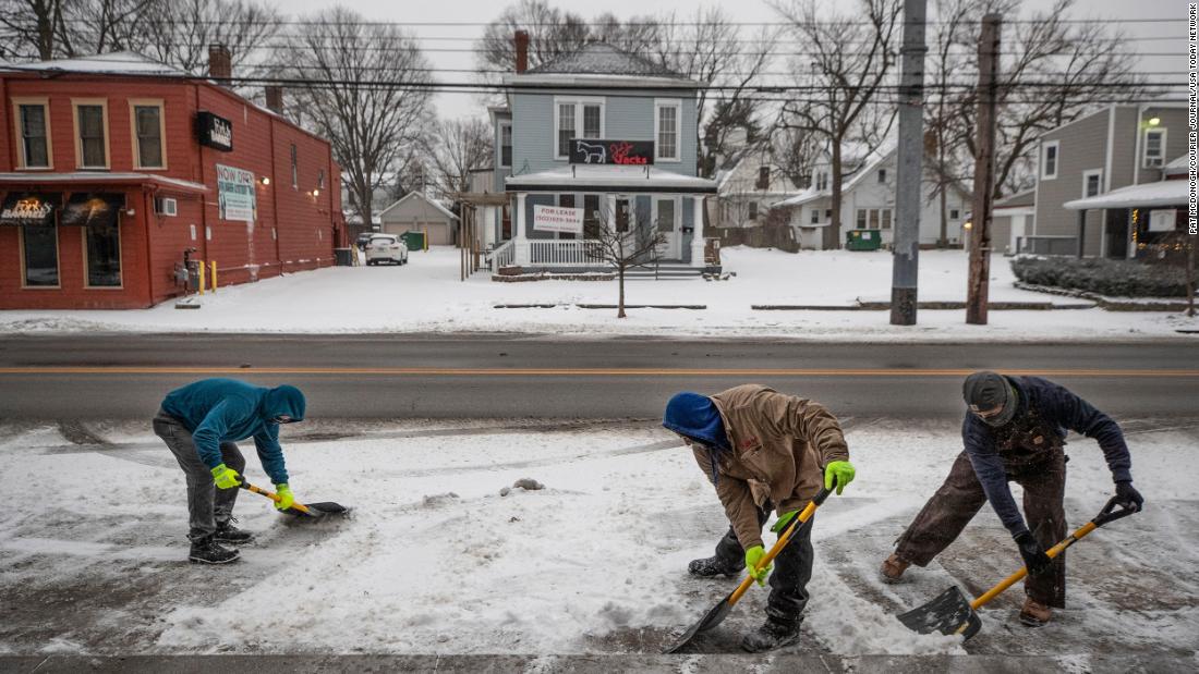 Men shovel ice and snow in front of shops in Louisville, Kentucky, on Monday.