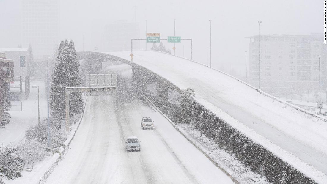 Cars drive along Interstate 705 as snow falls in Tacoma, Washington, on Saturday.