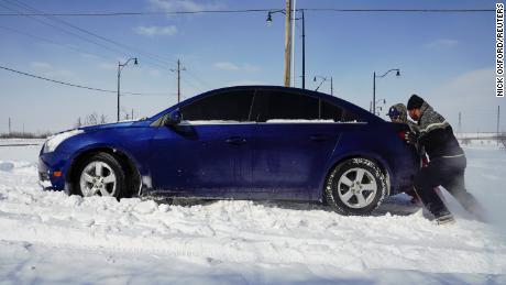 People work to free a car stuck in the snow during record breaking cold weather in Oklahoma City, Oklahoma, U.S., February 15, 2021.  REUTERS/Nick Oxford