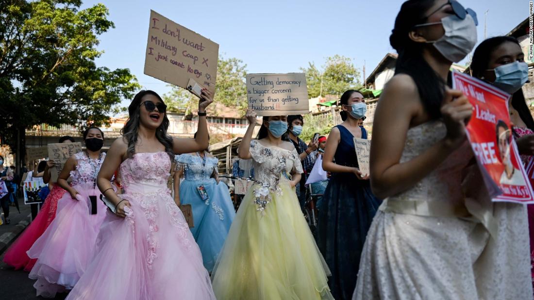 Women in wedding gowns holds up anti-coup placards in Yangon on February 10.