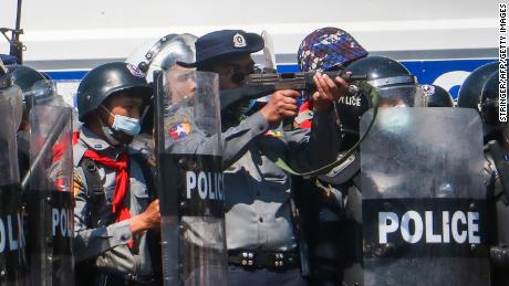 A police officer aims a gun during clashes with protesters taking part in a demonstration against the military coup in Naypyidaw on February 9.