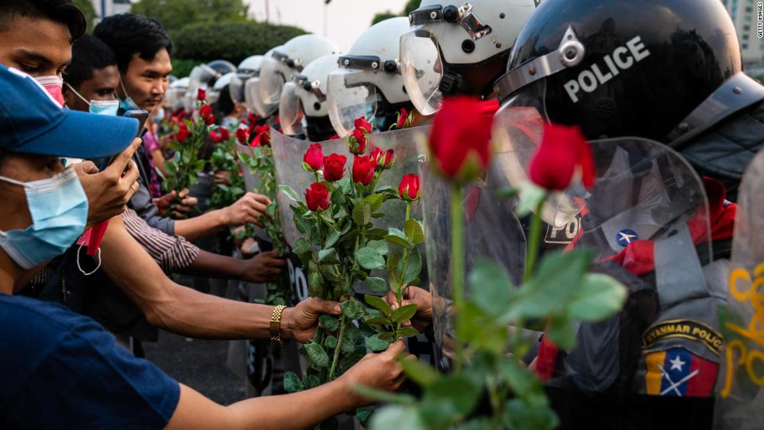 Protesters give roses to riot police in Yangon on February 6.