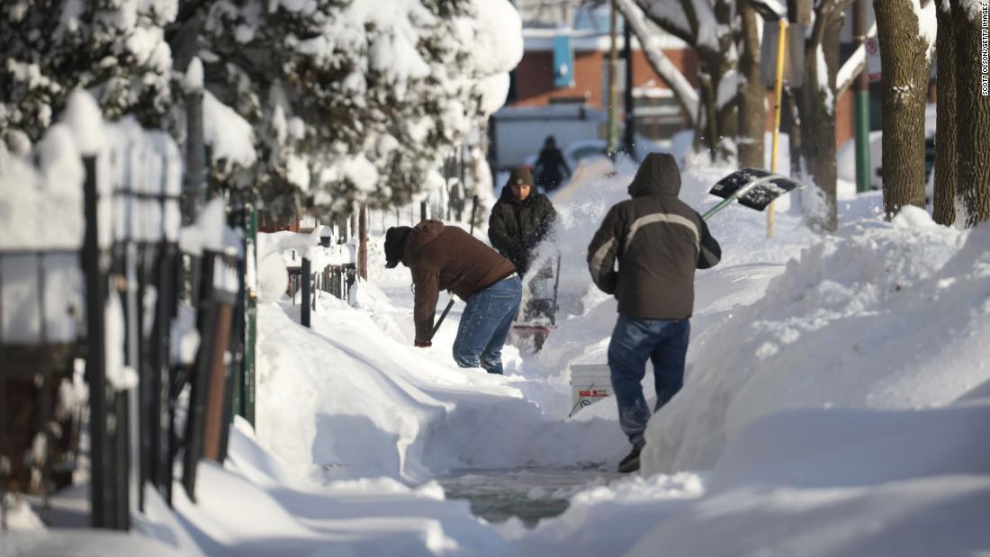 Residents clear snow from a sidewalk in Chicago on Tuesday.