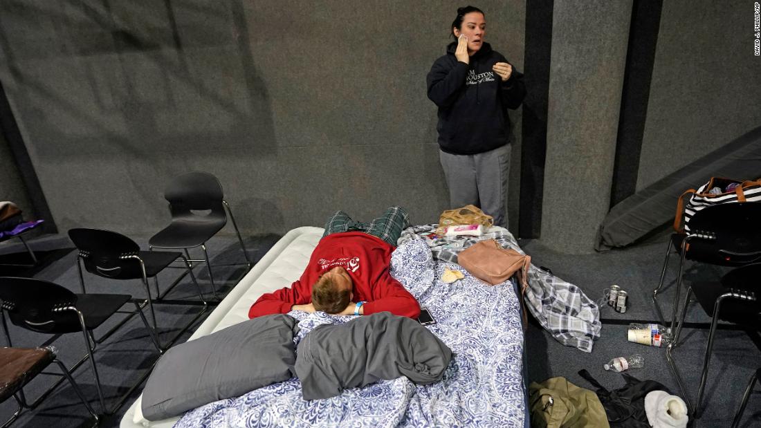 Bethany Fischer washes her face as her husband, Nic, lies on a mattress at a church in Houston on Tuesday. The couple lost power to their home.