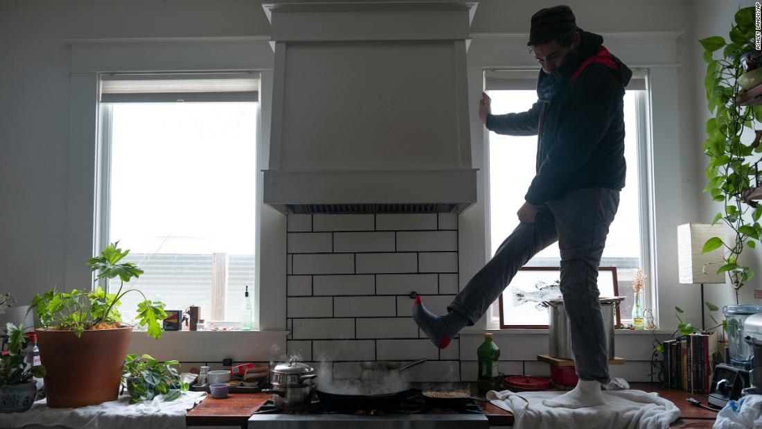 Jorge Sanhueza-Lyon stands on his kitchen counter to warm his feet over his gas stove in Austin.