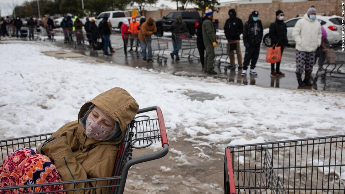 Camilla Swindle sits in a shopping cart as she and her boyfriend wait in a long line to enter a grocery store in Austin on Tuesday.