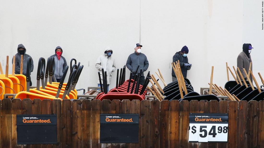 Customers wait outside a Home Depot to buy supplies in Pearland, Texas, on Wednesday. The store would let only one person in at a time because it had no power.