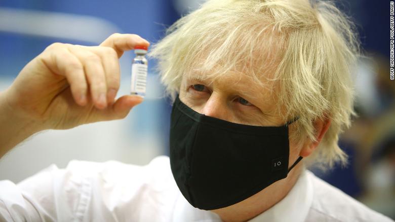 Johnson poses with a vial of the Oxford/AstraZeneca vaccine during a visit to the vaccination center at Cwmbran Stadium, Wales in February.