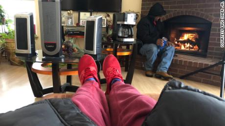 Eric Siner, Jr. warms his feet while his father sits by the fireplace after their neighbor hooked up their heaters to his generator. 