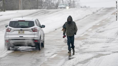 With many of the downtown sidewalks in Jackson, Mississippi covered with ice, a pedestrian walks on a street as cars pass him on Wednesday.