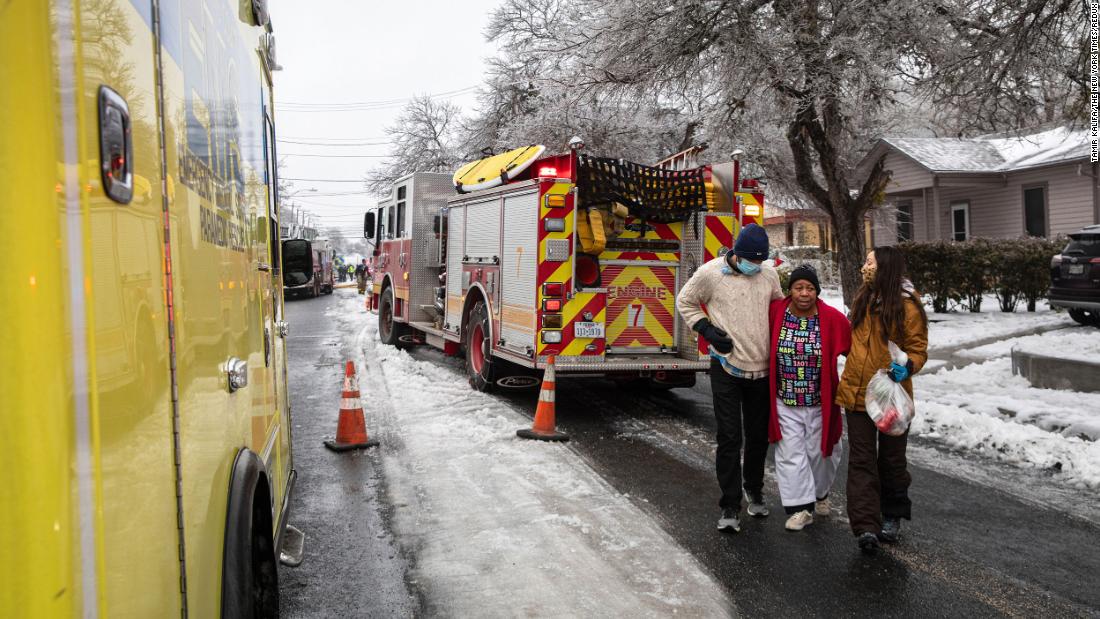 Nathan Halaney and Katherine Pena help their neighbor, Brenda Davis, from the scene of a nearby structure fire in Austin, Texas, on Wednesday.