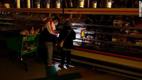 Customers use the light from a cell phone to look in the meat section of a grocery store in Dallas.