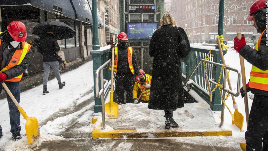 Metropolitan Transit Authority workers shovel the stairs of a subway station in New York City on Thursday.