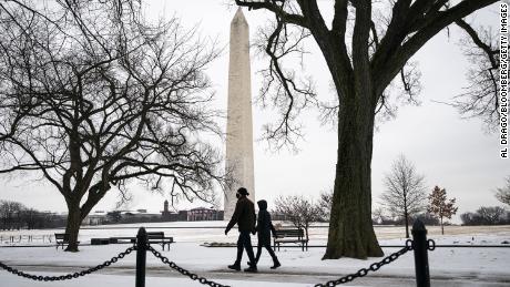 Pedestrians walk in the snow near the Washington Monument in Washington, D.C.