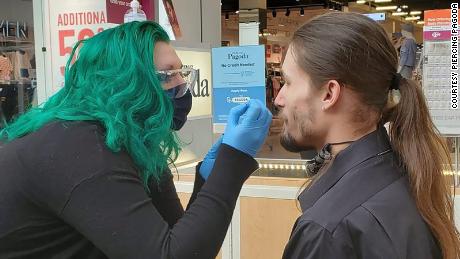  Zengota le hace un piercing en la nariz a un cliente en el centro comercial Tacoma.