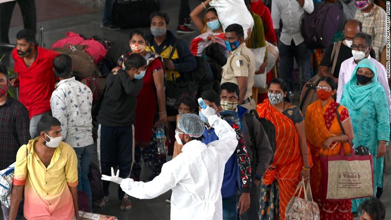 A health worker checks the body temperature of arriving passengers at a railway terminus in Mumbai on January 6, 2021.