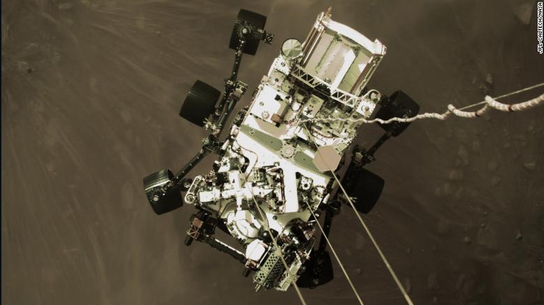 This shot from a camera on Perservance&#39;s &quot;jetpack&quot; captures the rover in midair, just before its wheels touched down.