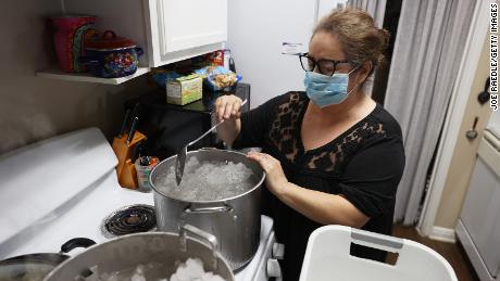 Marie Maybou melts snow on her kitchen stove in Austin on Friday. She is using the water to flush her home&#39;s toilets after the city water stopped running.