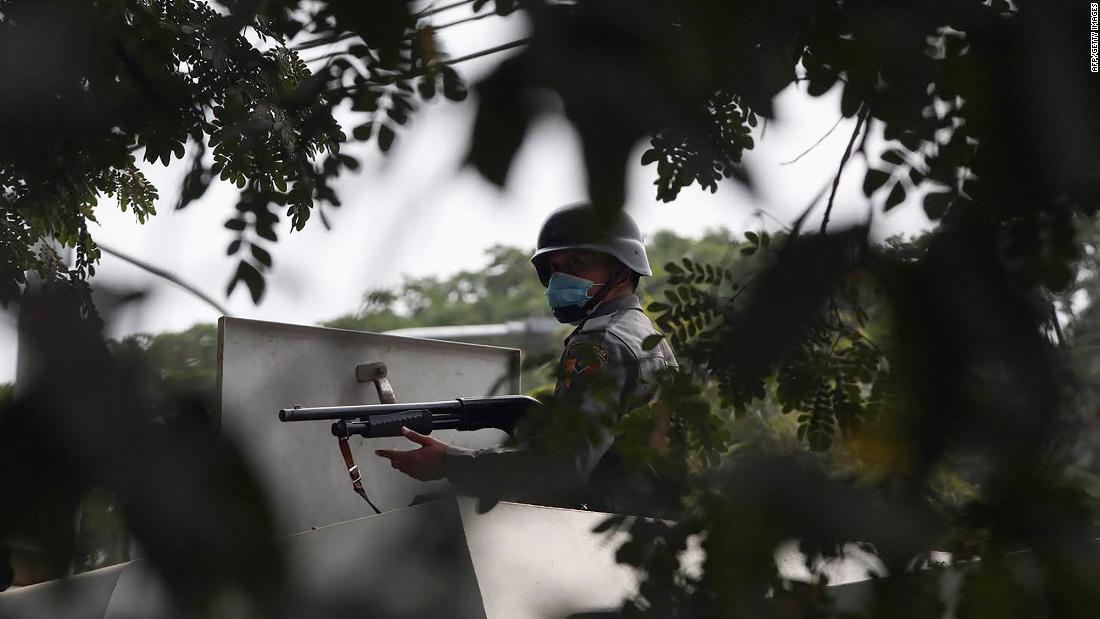 A police officer aims a gun toward protesters during a demonstration in Mandalay on February 20.