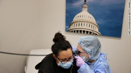 Nurse Practitioner Diane Alvarez (R) examines Jackie Saravia after testing her for the novel coronavirus at the Velocity Urgent Care April 15, 2020 in Woodbridge, Virginia.