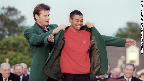 Faldo helps 1997 Masters champion Woods into his green jacket.