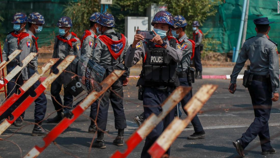 A police officer films protesters near the Indonesian Embassy in Yangon on February 24.