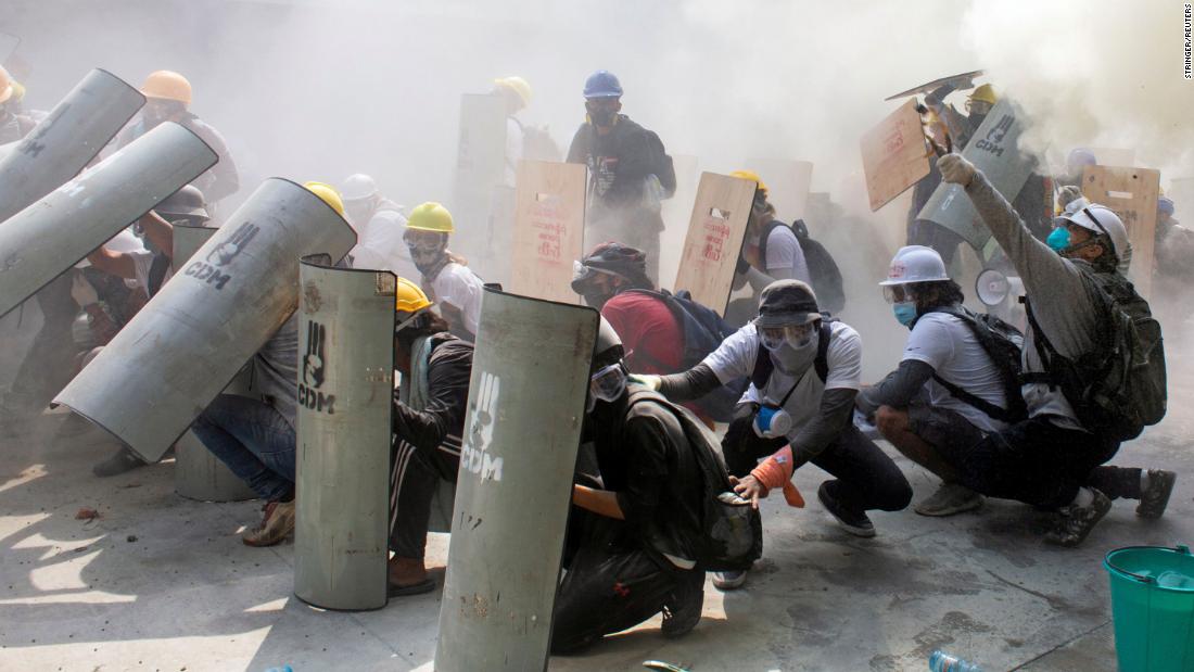 Protesters take cover as they clash with police in Yangon on February 28.