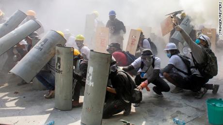 Protesters take cover as they clash with riot police officers during a protest against the military coup in Yangon, Myanmar, February 28.