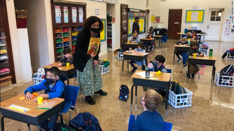 Leigh Oquendo, a kindergarten teacher at Hawthorne Scholastic Academy in Chicago, answers a masked student&#39;s question on the first day of in-person learning for K-5 students in the city.