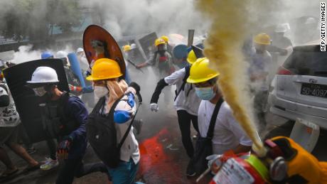 متظاهر يستخدم مطفأة حريق بينما يعمل آخرون يحملون دروعًا محلية الصنع خلال مظاهرة في يانغون يوم الأربعاء.